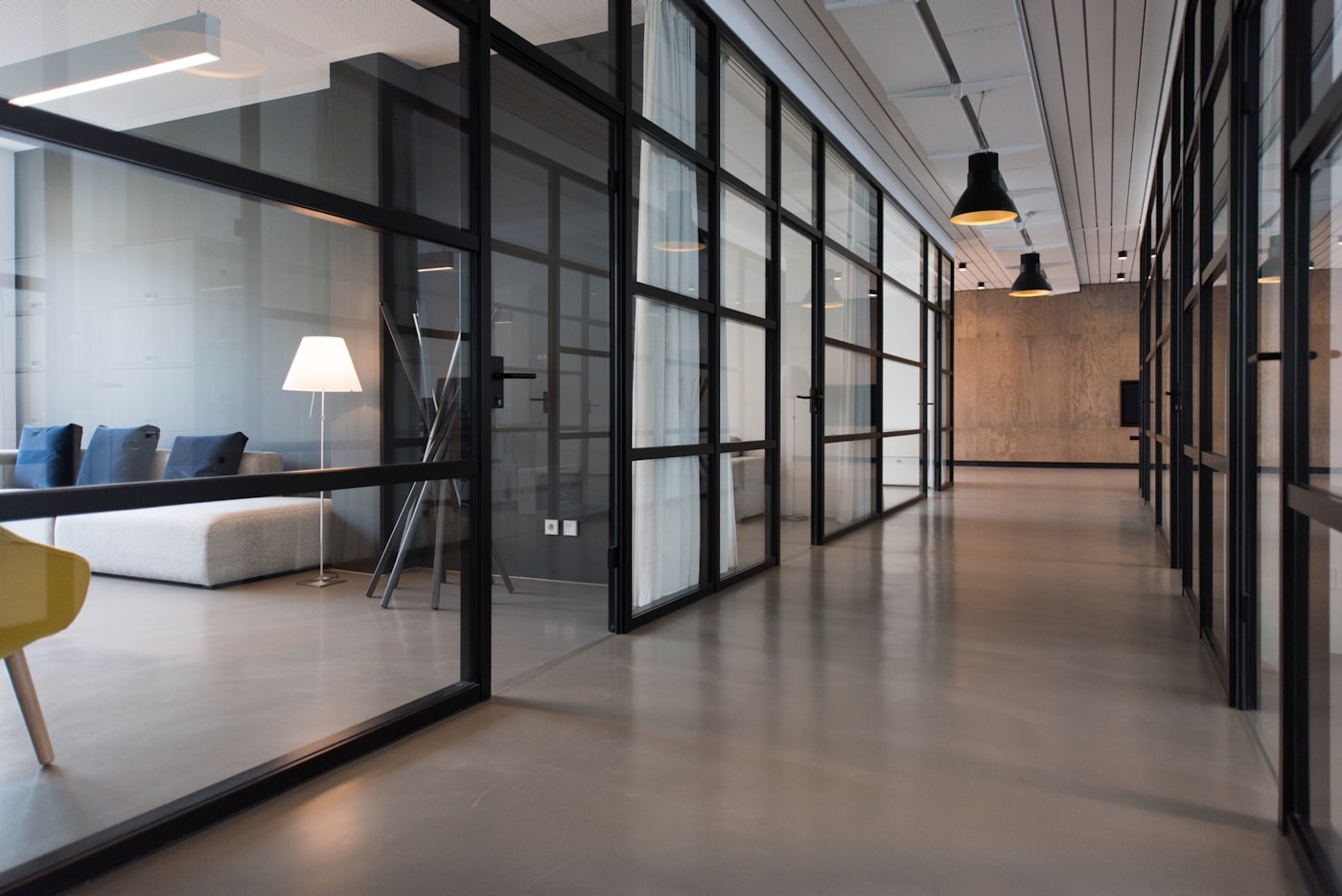 A bright institutional office corridor with glass-walled rooms